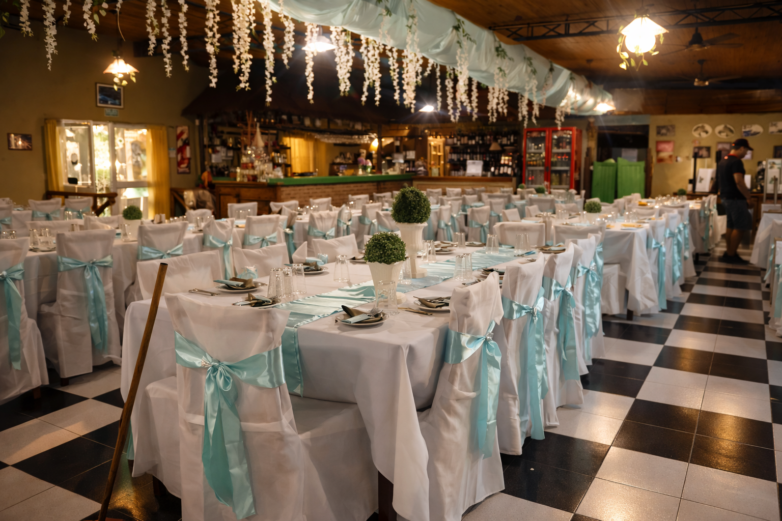 Un salón de eventos formal preparado para un banquete, con manteles blancos, lazos azul claro en las sillas