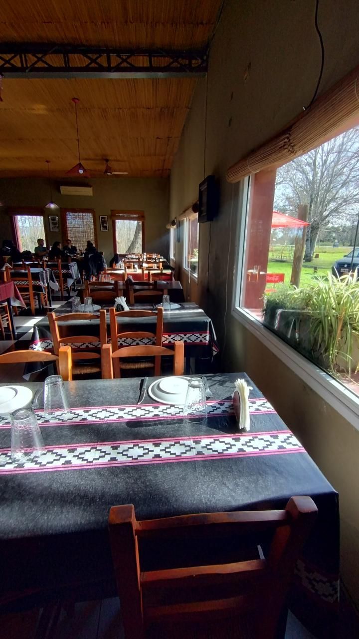Vista interior de un restaurante rústico con muebles de madera, manteles estampados