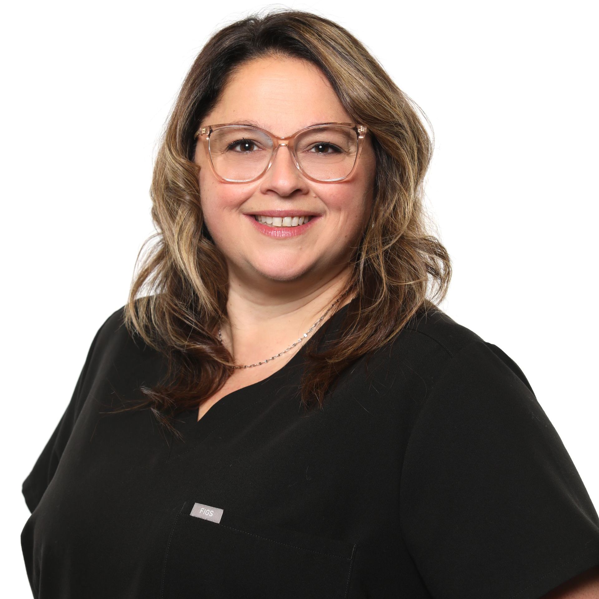 Femme portant des lunettes, souriante, vêtue d'un haut de gommage noir, debout sur un fond blanc.