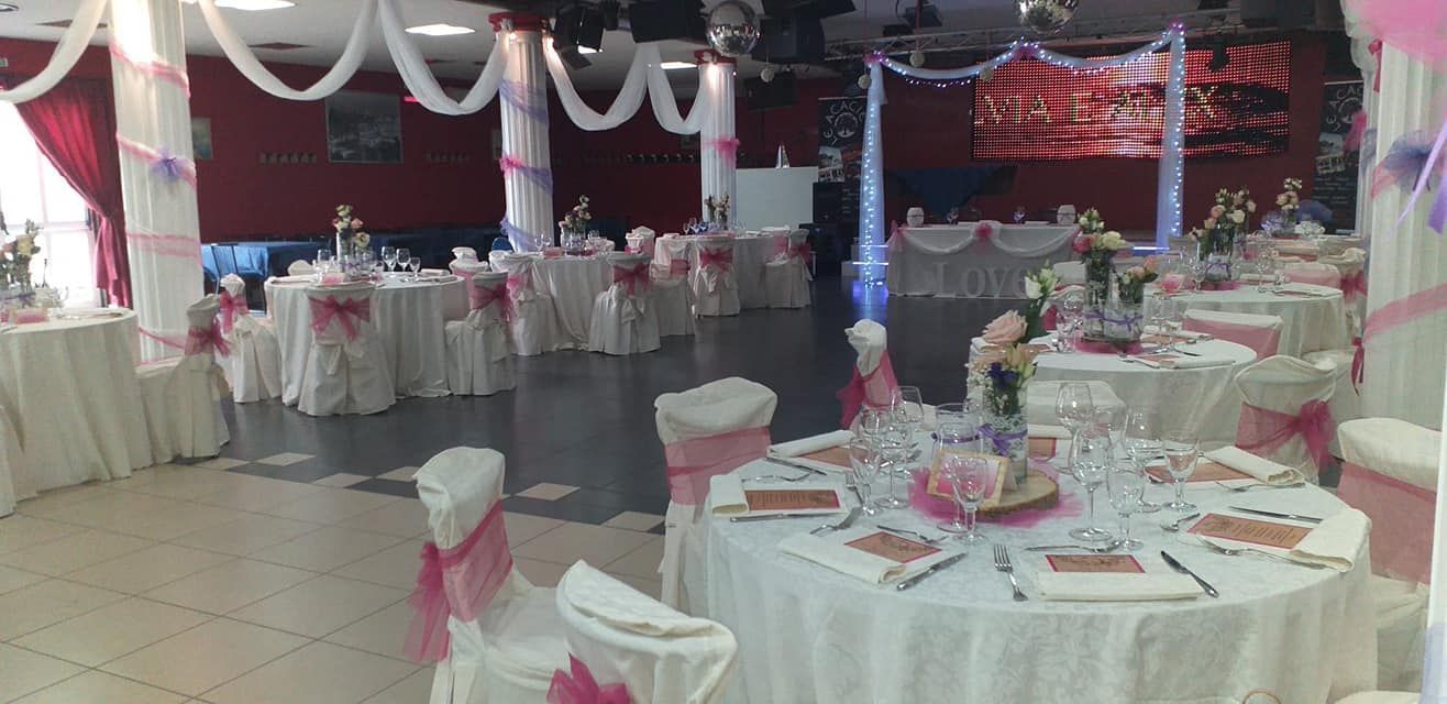 Sala per banchetti decorata con tavoli rotondi ricoperti da tovaglie bianche e rosa.