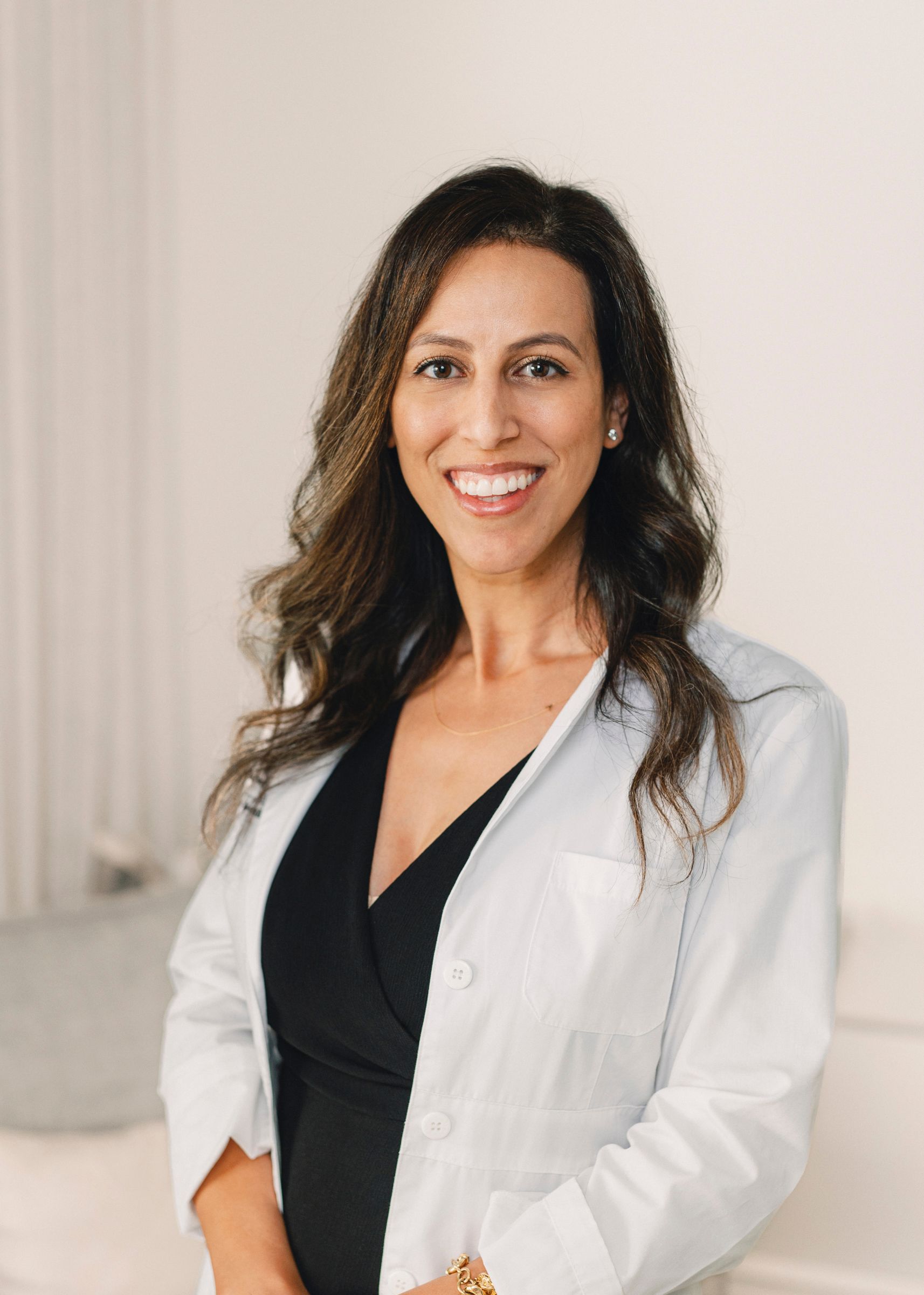 a portrait of Dr. Jackie Beshir, Board-Certified Dermatologist wearing a pink button down blouse