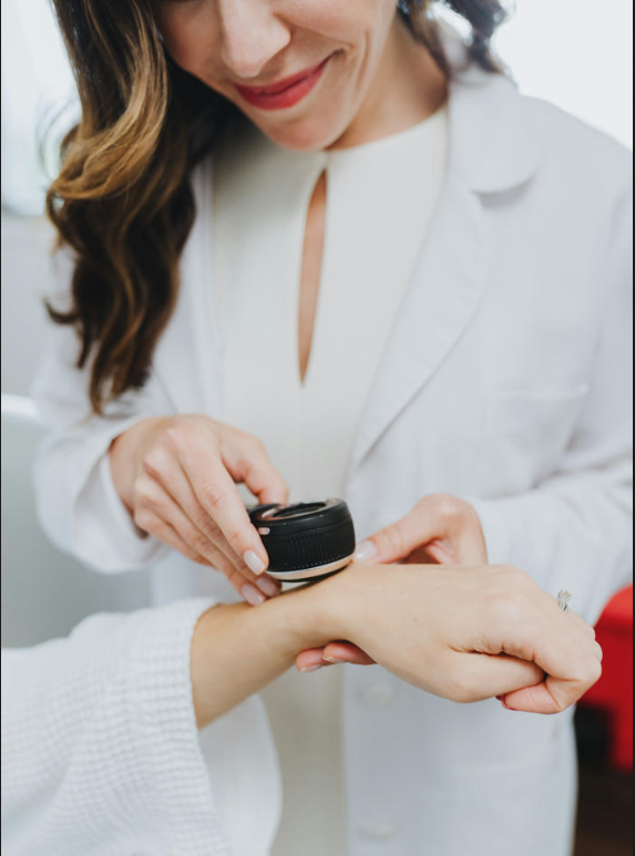 dermatologist wearing gloves examines patient's hand with lighted scope