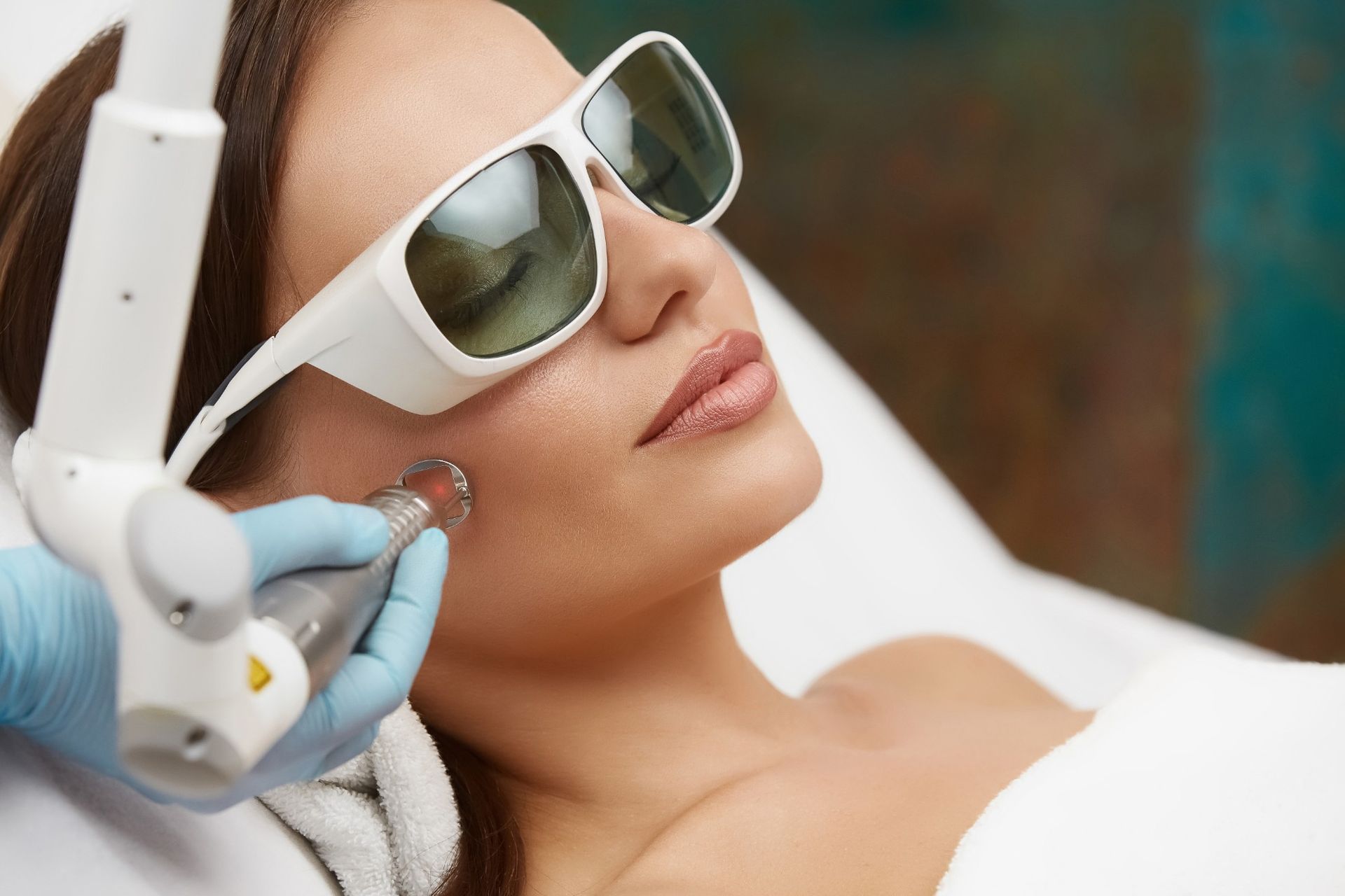 A woman is getting a laser treatment on her face.