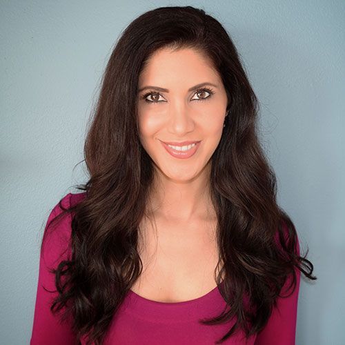 a portrait of Dr. Reyhaneh Hamidi, Board-Certified Dermatologist wearing a hot pink blouse