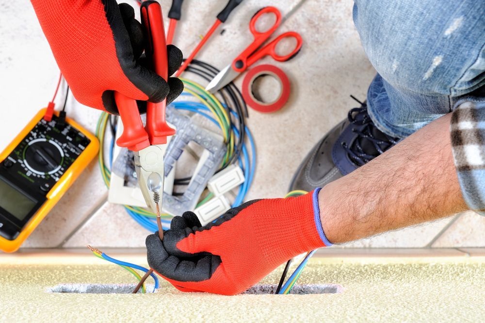 Electrician Working On Wiring With Red Gloves And Tools — Stanayr Electrical in Gulliver, QLD