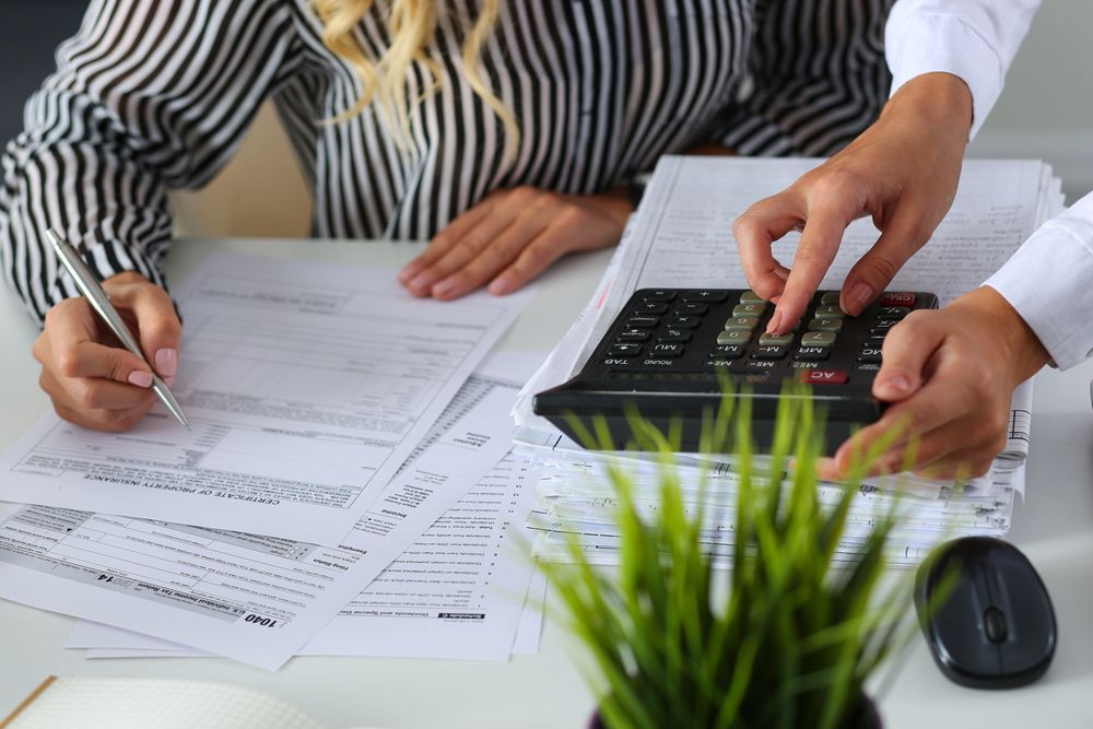 Two People Working On Financial Documents With A Calculator — Stanayr Electrical in Gulliver, QLD