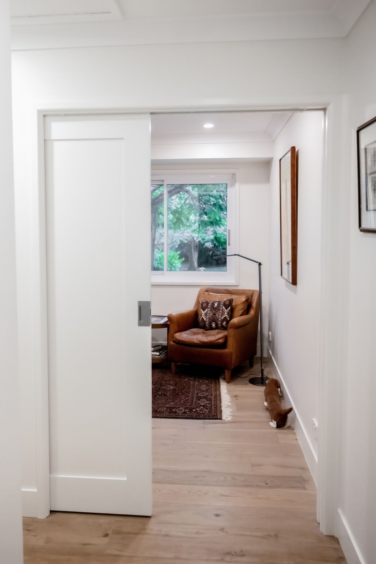 White Hallway Opens to a Cozy Room With a Leather Chair — Prime Built Group in Moss Vale, NSW