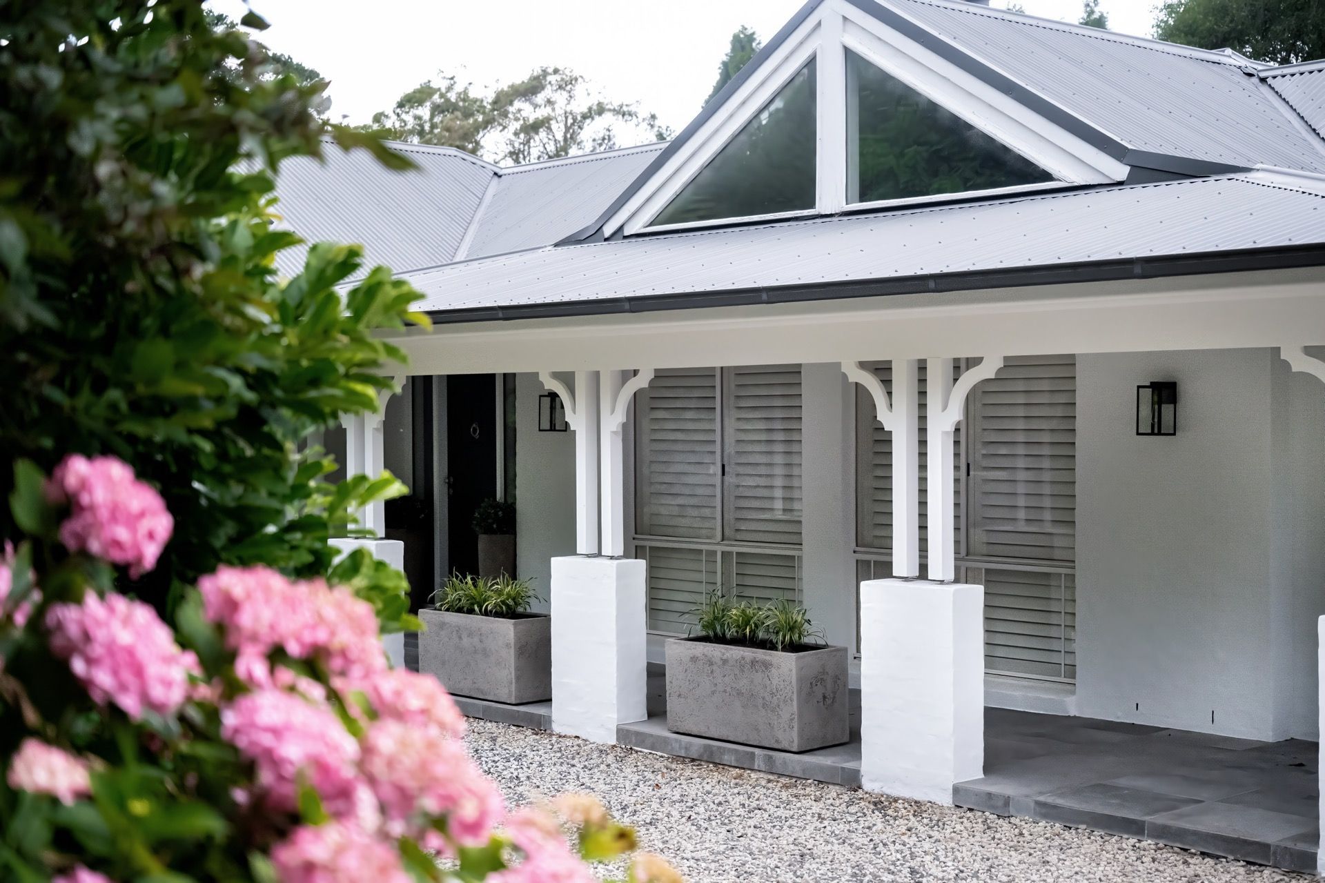 White cottage with a porch, gravel path, and pink flowers in the foreground — Prime Built Group in Bowral, NSW