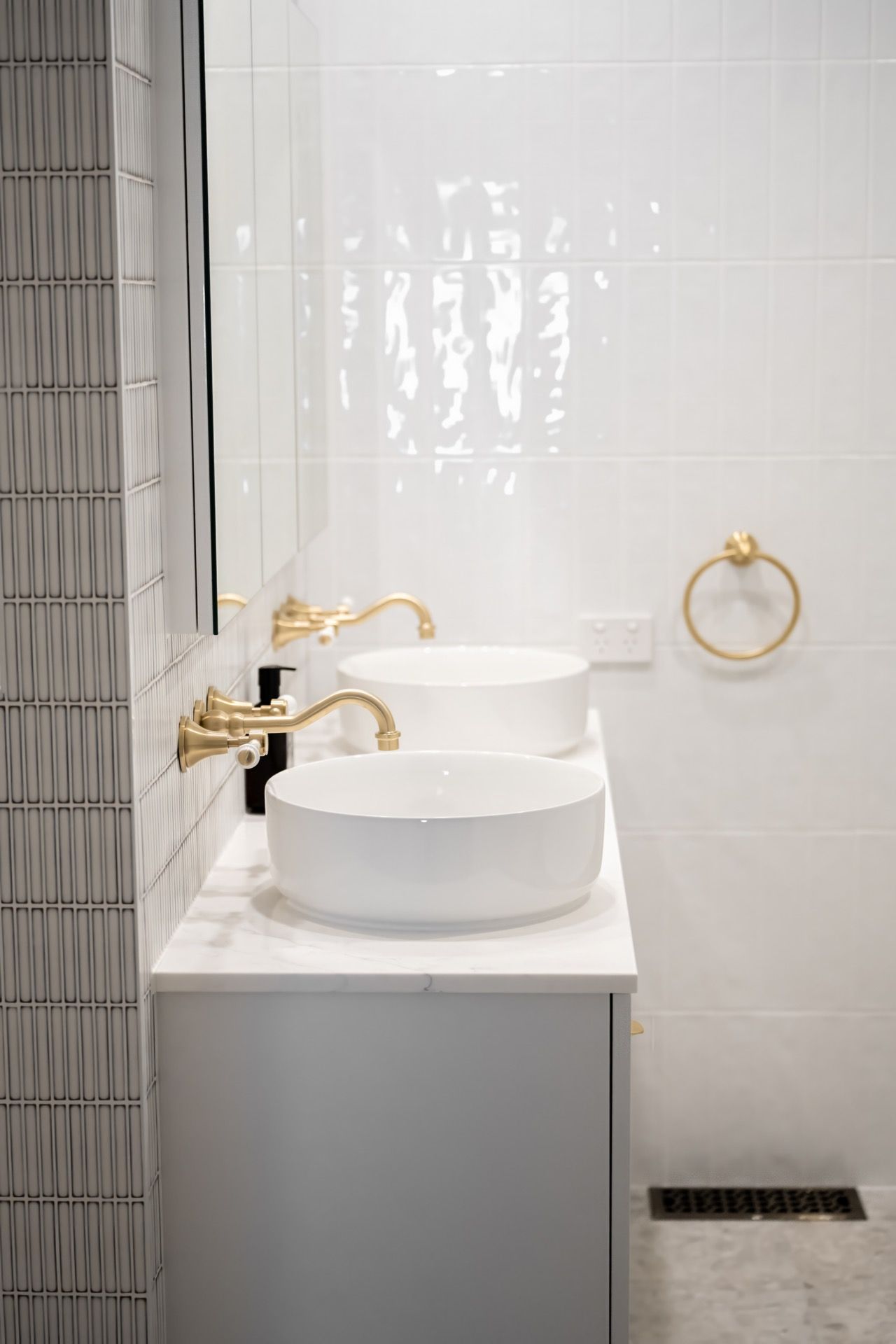 Modern bathroom vanity with two white vessel sinks, gold faucets, and white tiled walls — Prime Built Group in Bowral, NSW