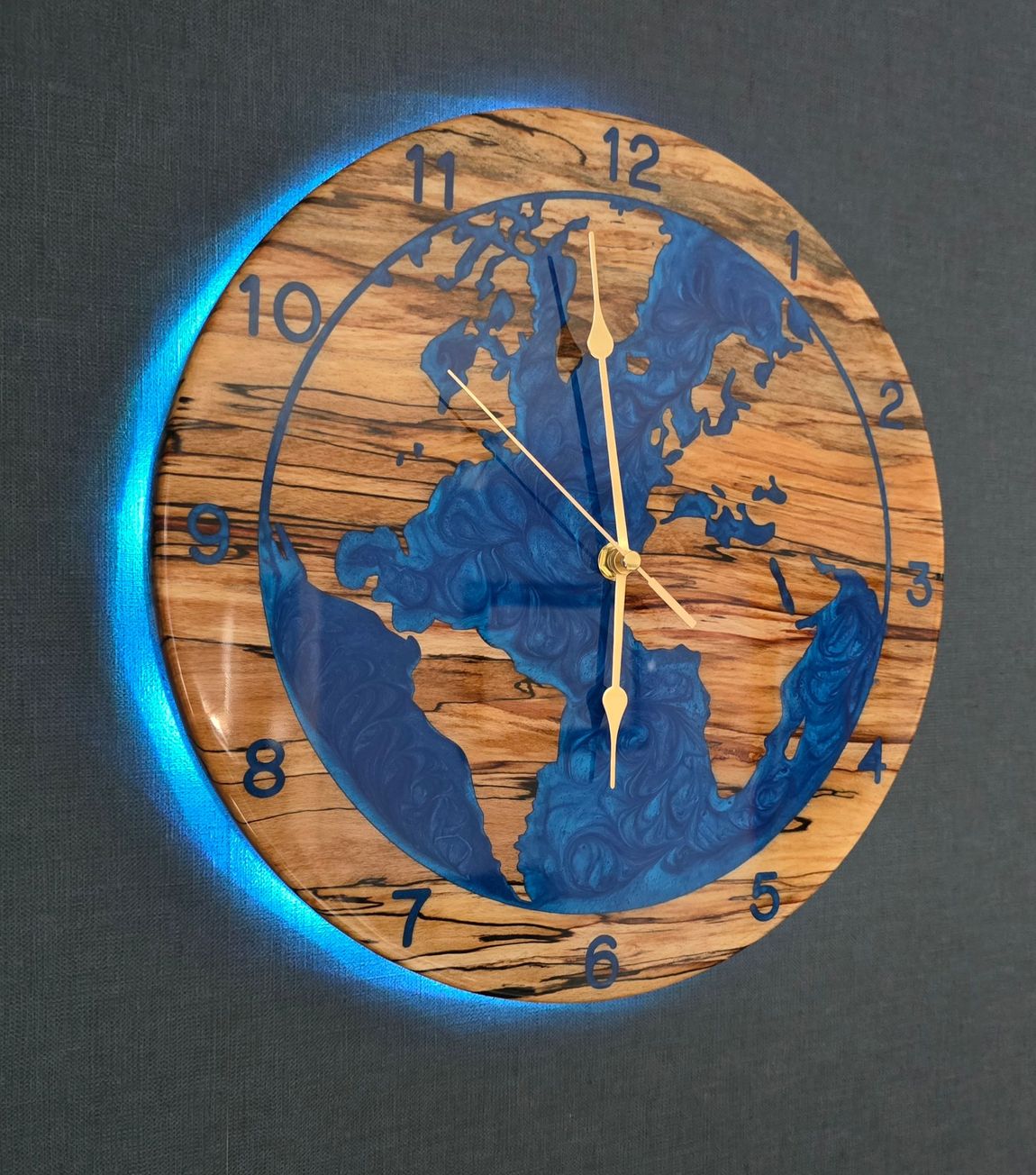 Handcrafted Planet Earth wall clock in white oak with blue resin oceans and integrated LED backlighting by The Humble Woodshed.