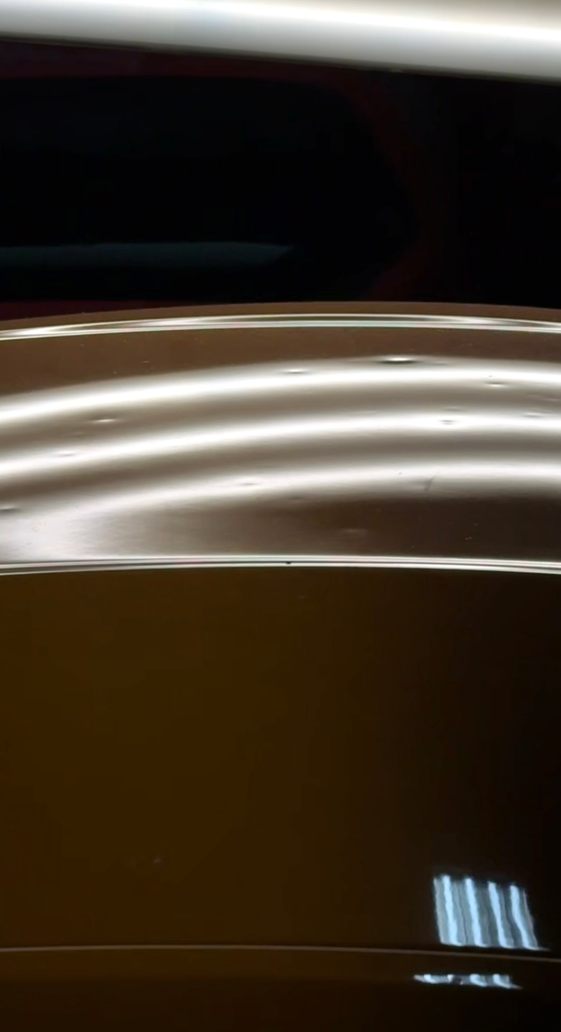 Car door with dents, illuminated by overhead lights showing the damage.