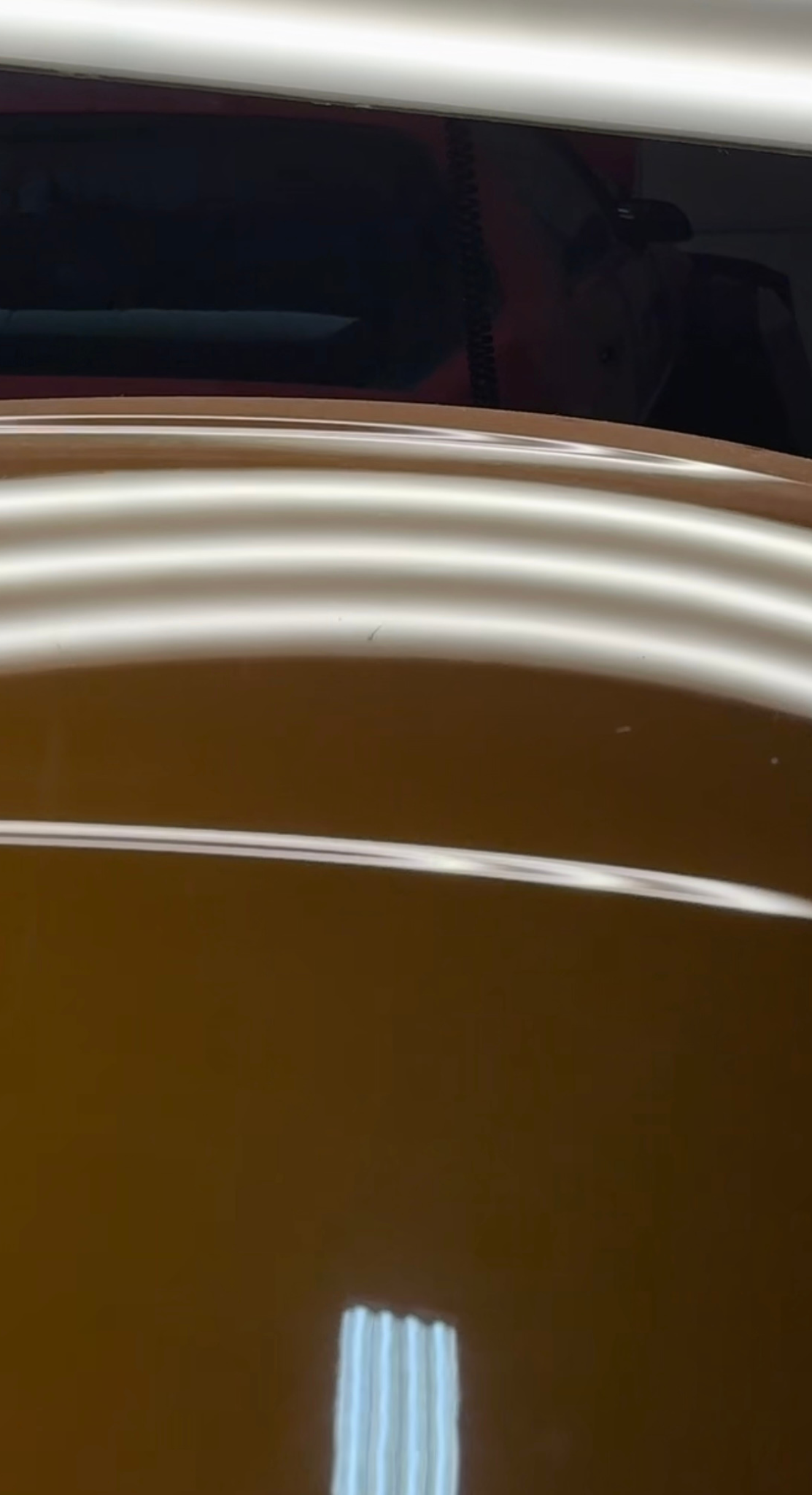 Metallic car surface with multiple shallow dents reflected in a light board.