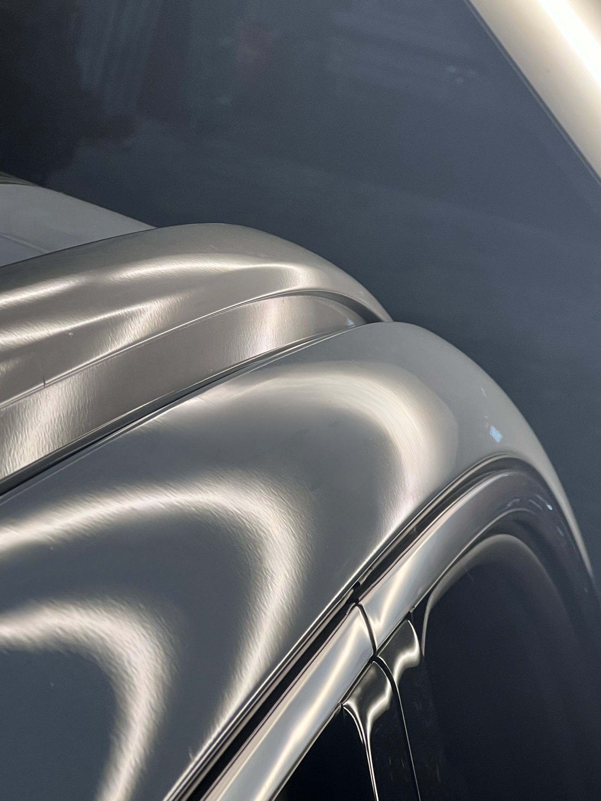 Close-up of a shiny, black car roof reflecting light in a dark setting.