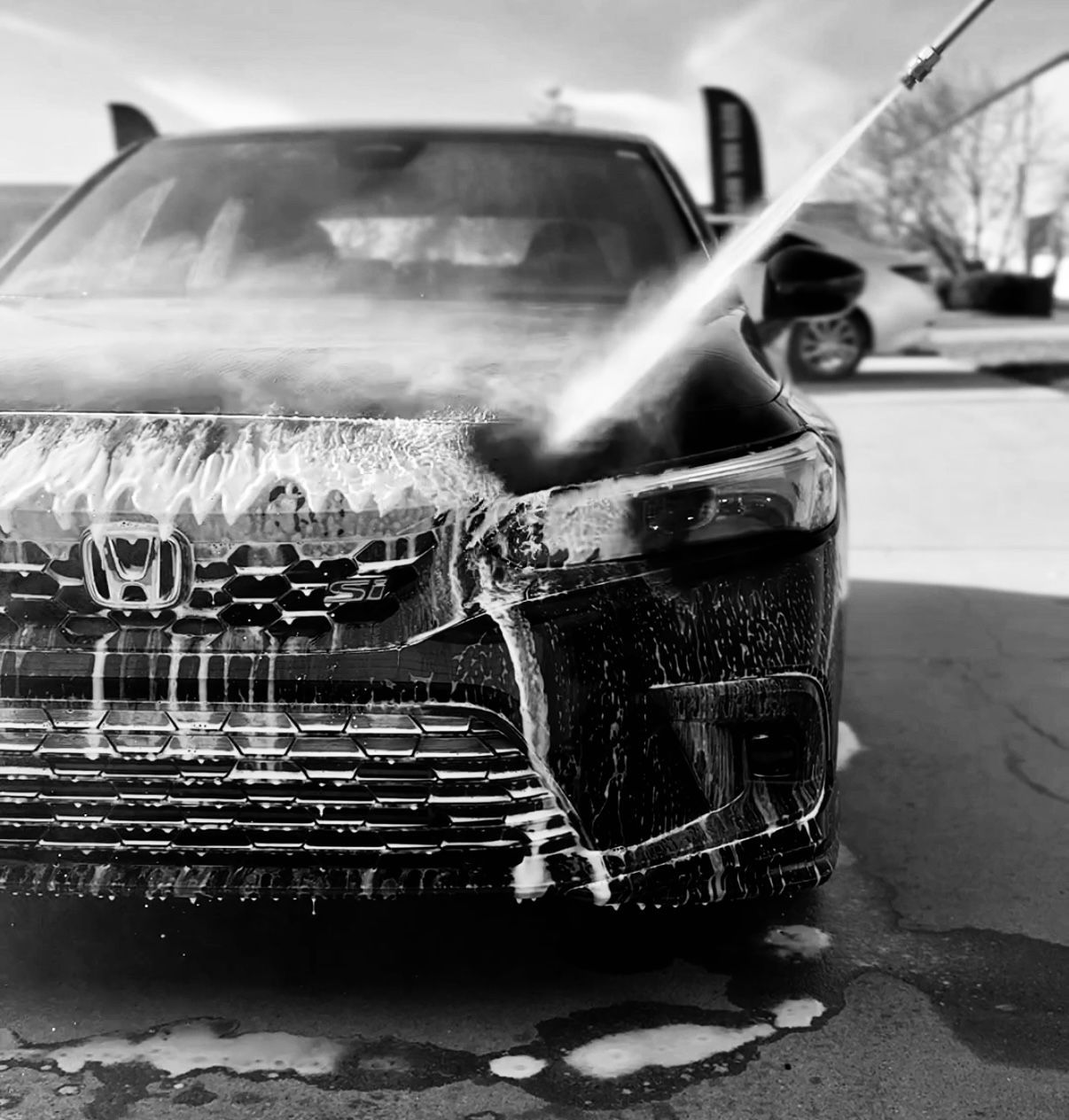A black car being washed with soap and water at a car wash.