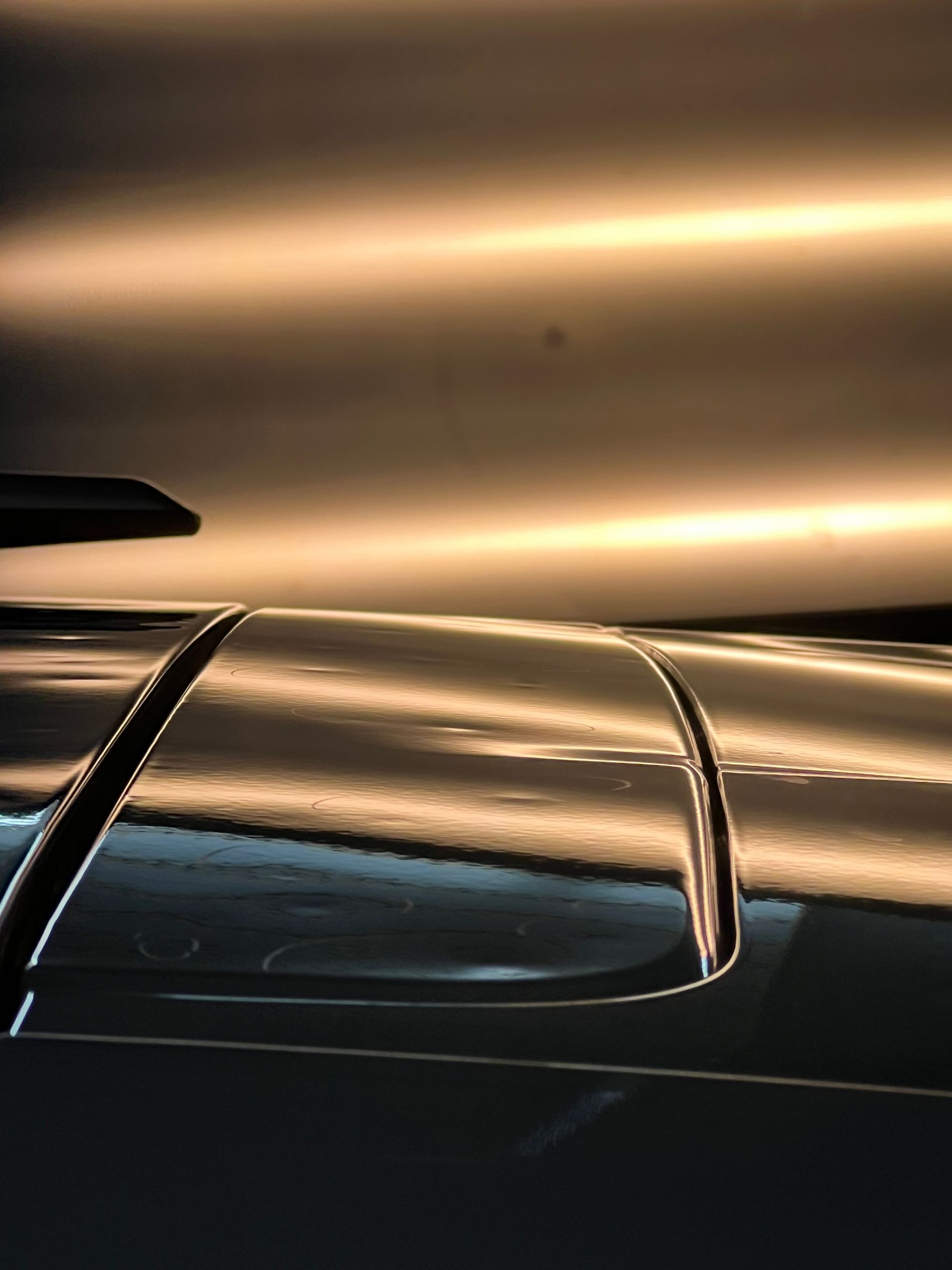 Shiny car panel reflecting horizontal lights.