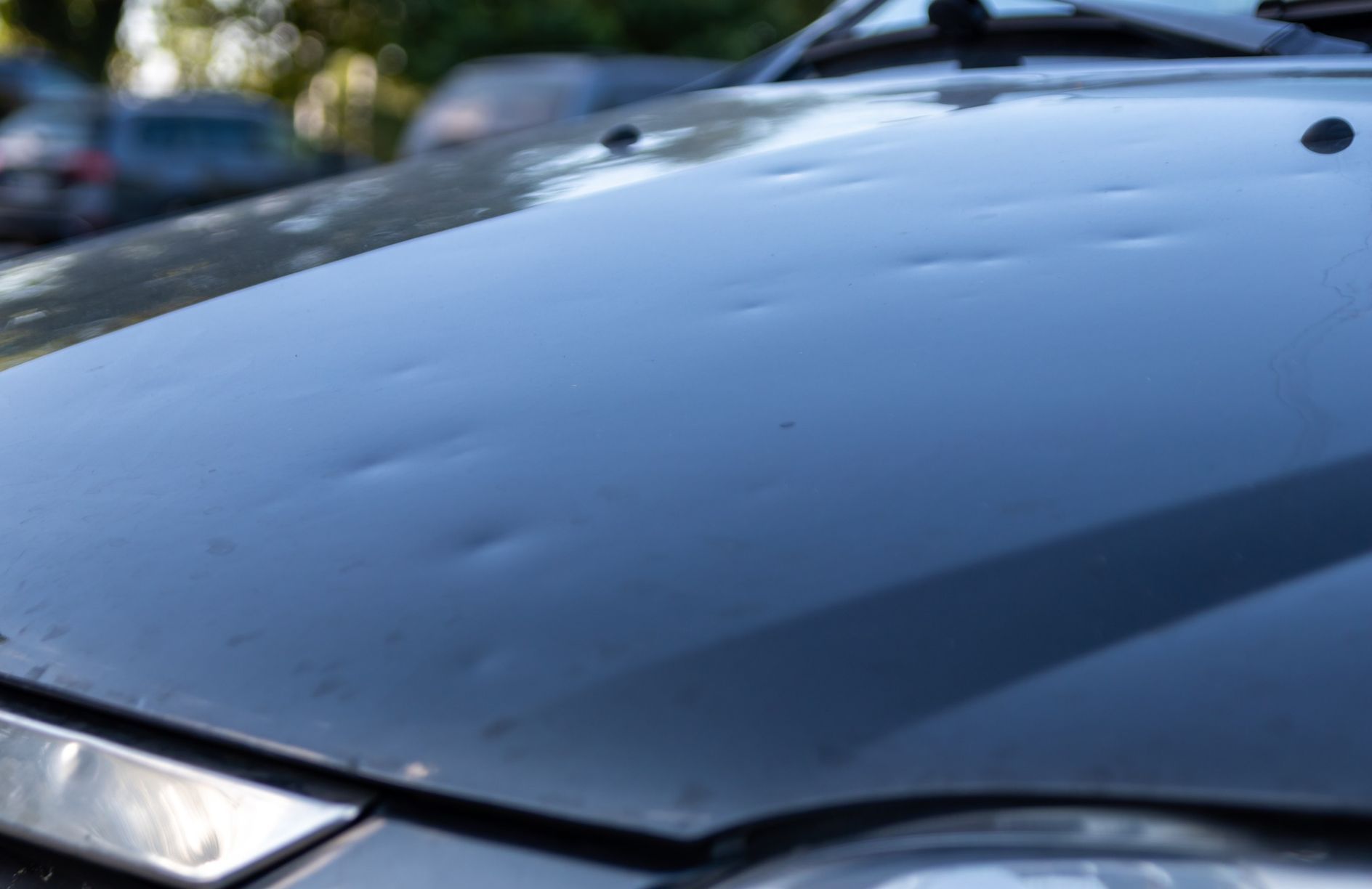 Car hood with multiple dents from hail damage.