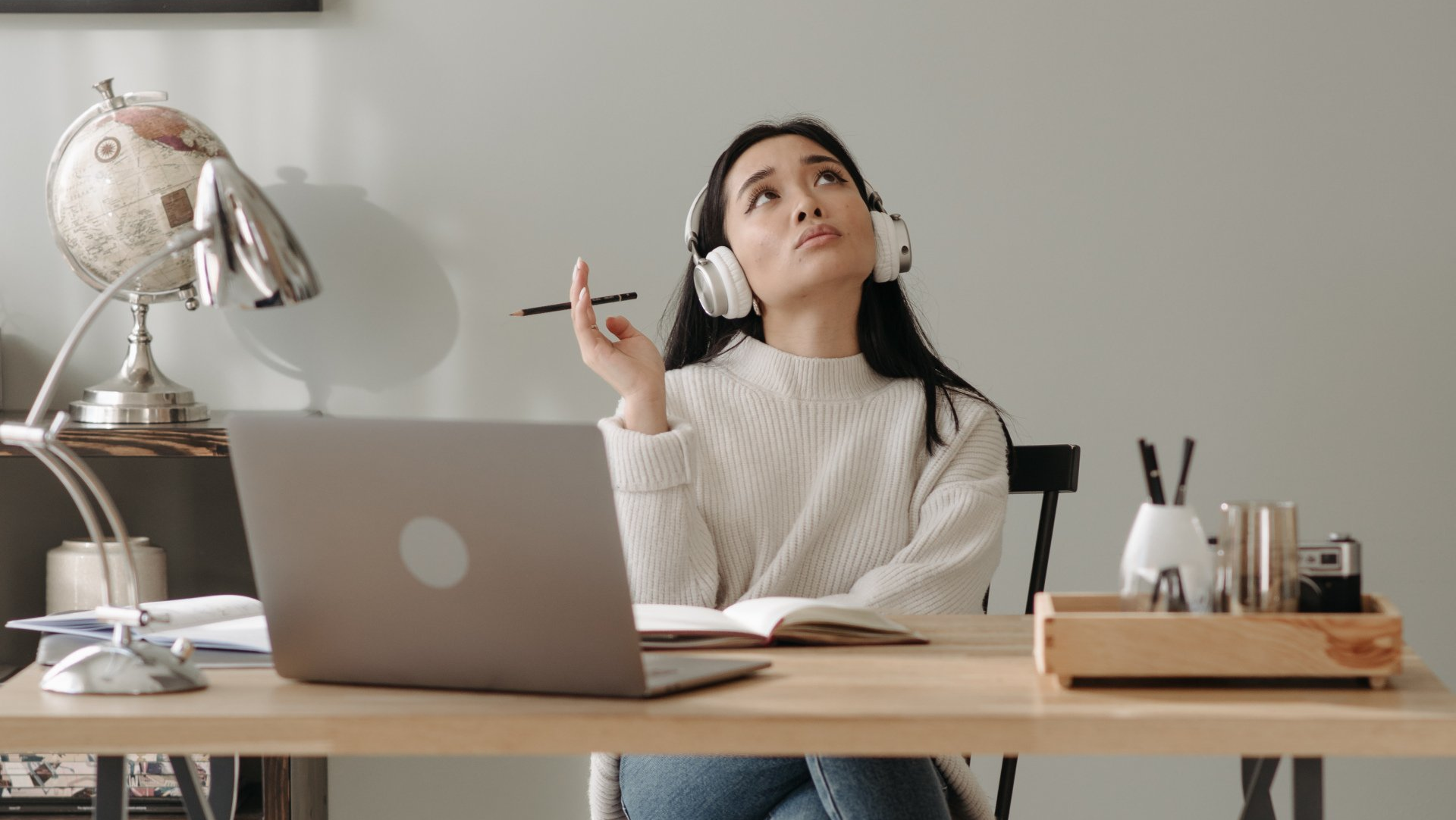 A woman is sitting at a desk with a laptop and headphones on.