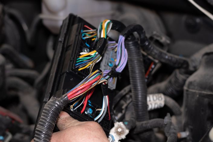 Close-up of a car’s exposed wiring harness and electrical connectors inside the dashboard area