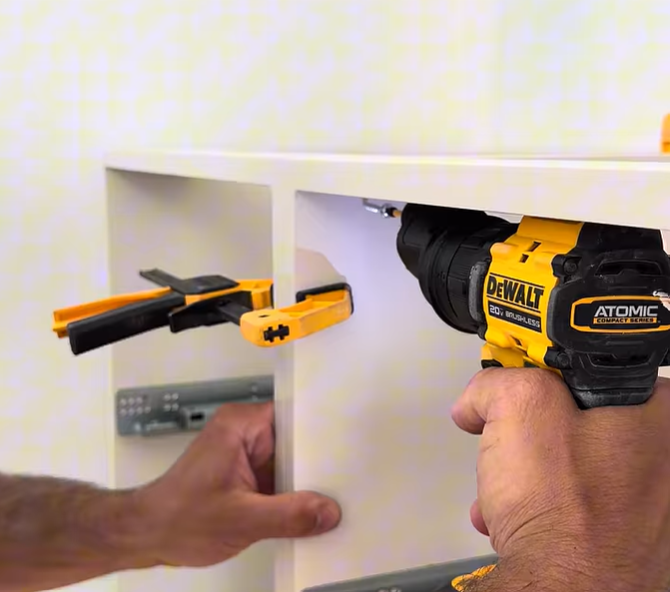 Worker in blue overalls measuring a white countertop in a bright kitchen with tools nearby