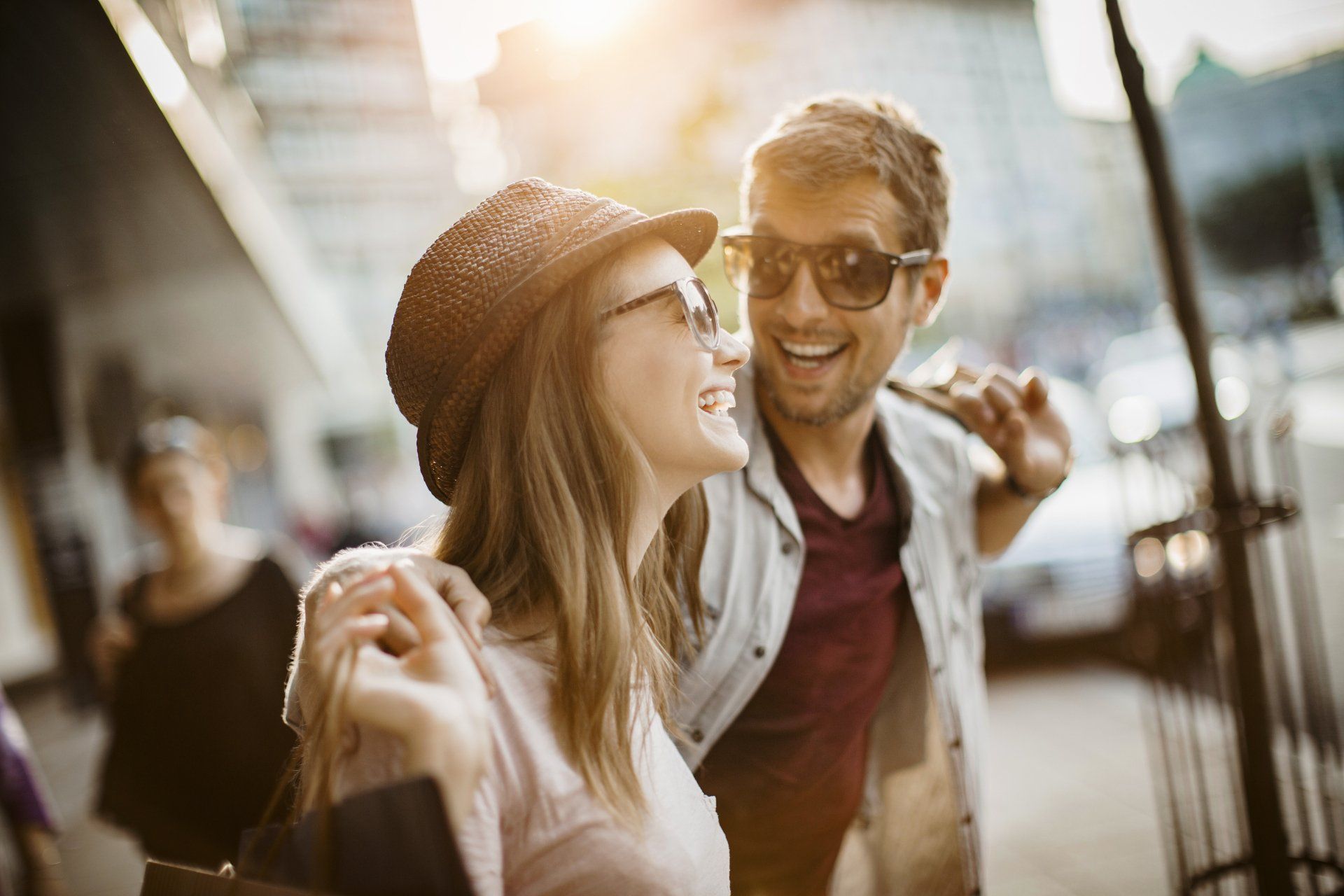 A man and a woman are walking down the street . the woman is wearing a hat and sunglasses.
