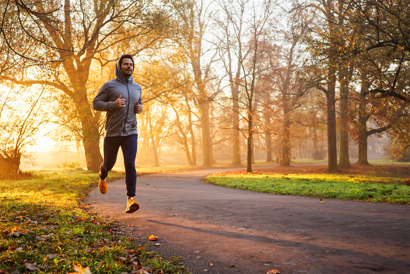 A man is running on a path in a park at sunset.