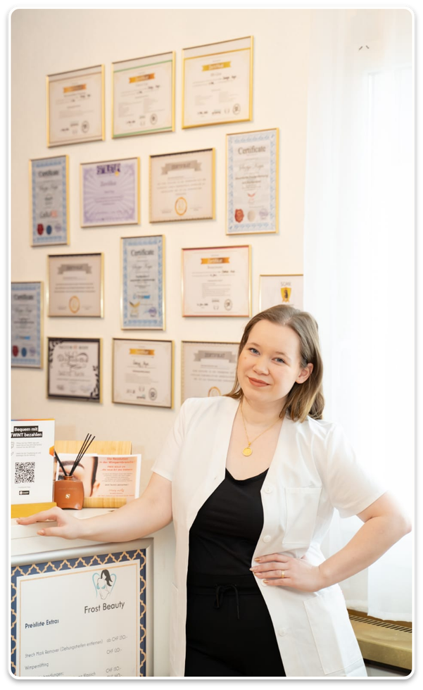 Eine Frau steht vor einer Wand voller Zertifikate.