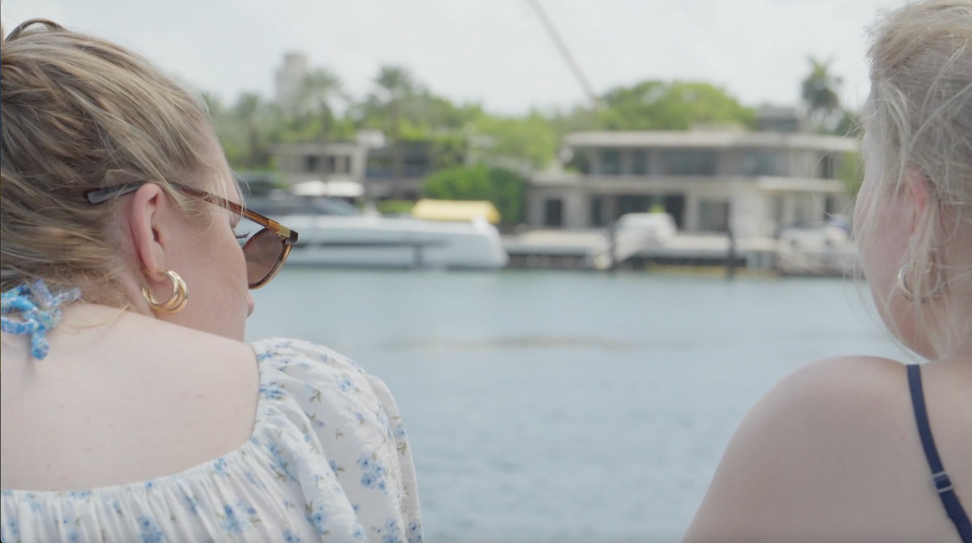 Two women enjoying Miami sightseeing while looking at waterfront mansions during a celebrity homes boat tour