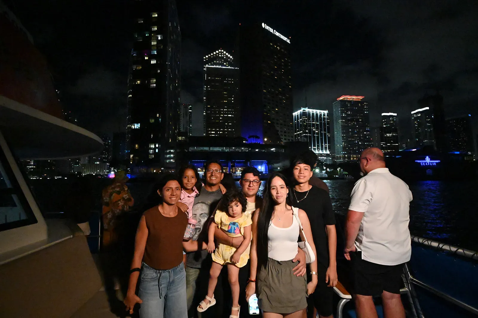 Families enjoying a nighttime sightseeing boat tour with Downtown Miami waterfront views