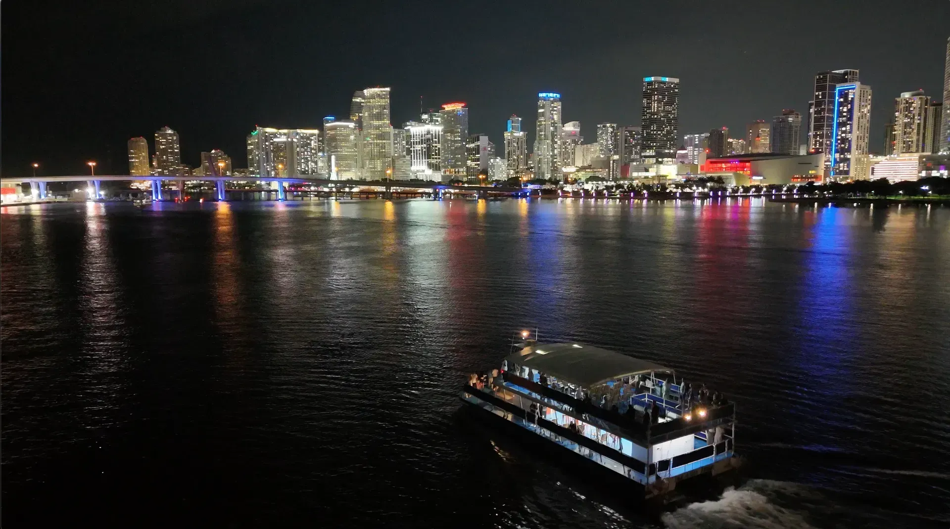 Boat tour crossing the water with Downtown Miami city reflections during a Miami Evening Cruise