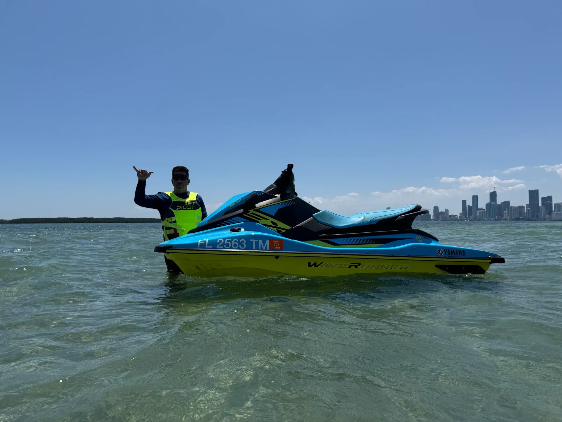 Miami Jet Ski Tour guide standing in Biscayne Bay next to a jet ski with skyline views