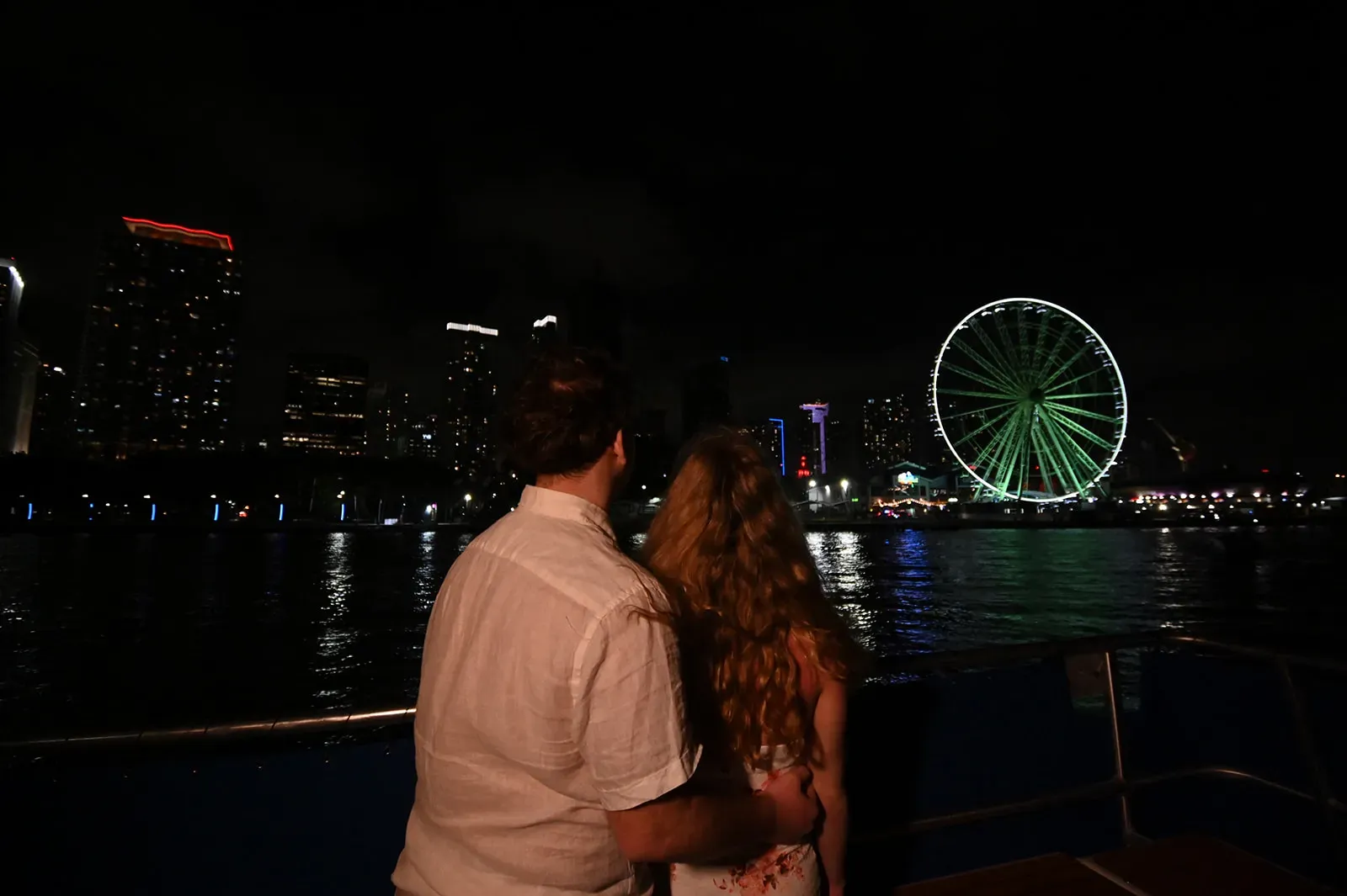 Couple enjoying the Miami skyline during a nighttime sightseeing cruise on Biscayne Bay
