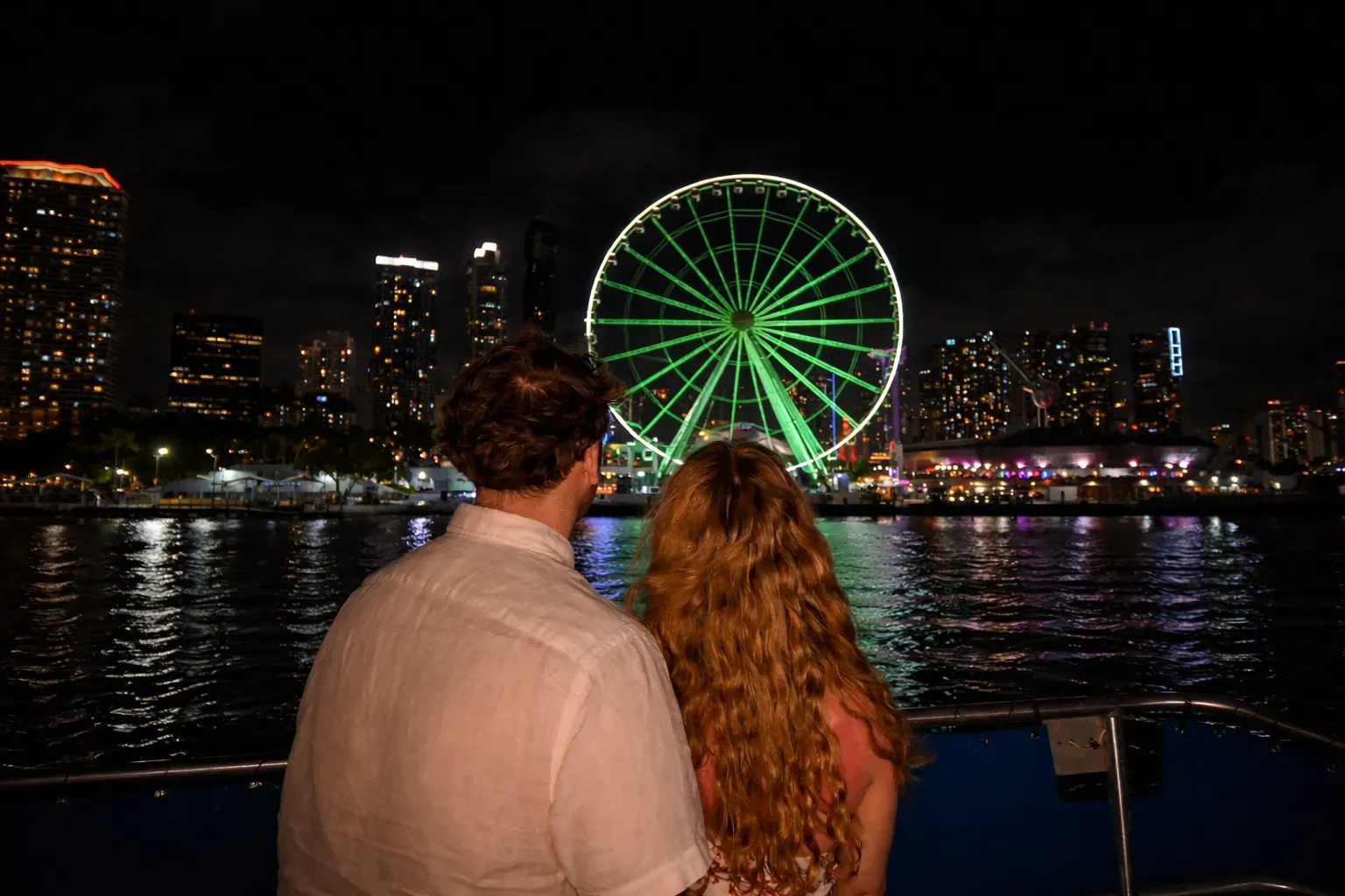 Passengers enjoying the illuminated Miami waterfront during a night cruise.