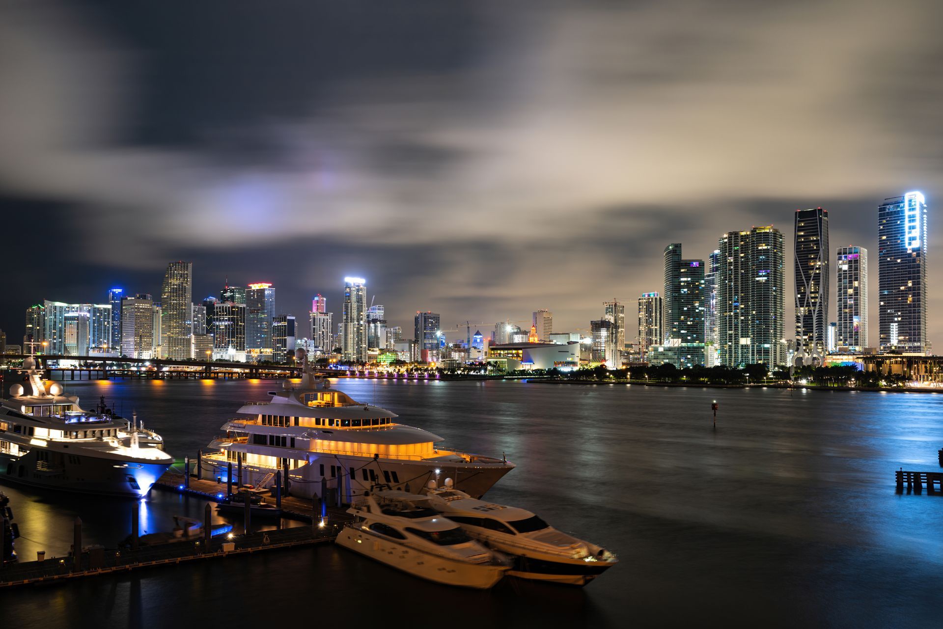 Miami skyline at night reflecting on the water with illuminated downtown buildings.