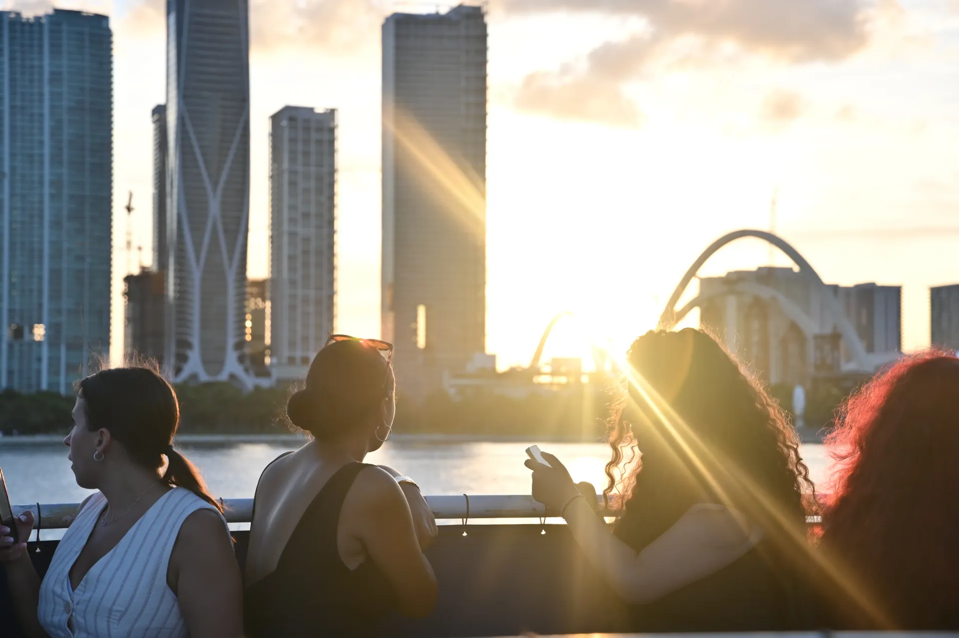 Passengers watching the sunset over the Miami waterfront during a sightseeing cruise.