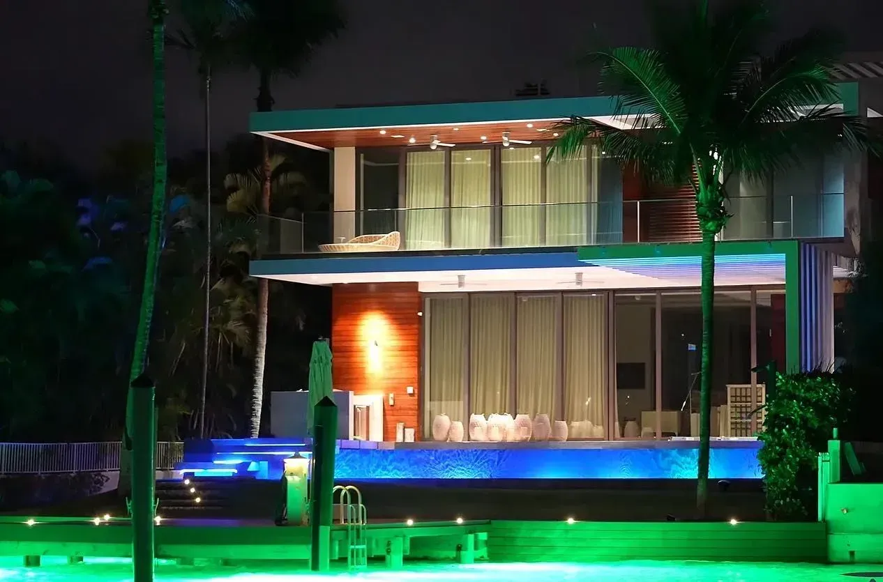 Modern waterfront home illuminated at night along Biscayne Bay in Miami
