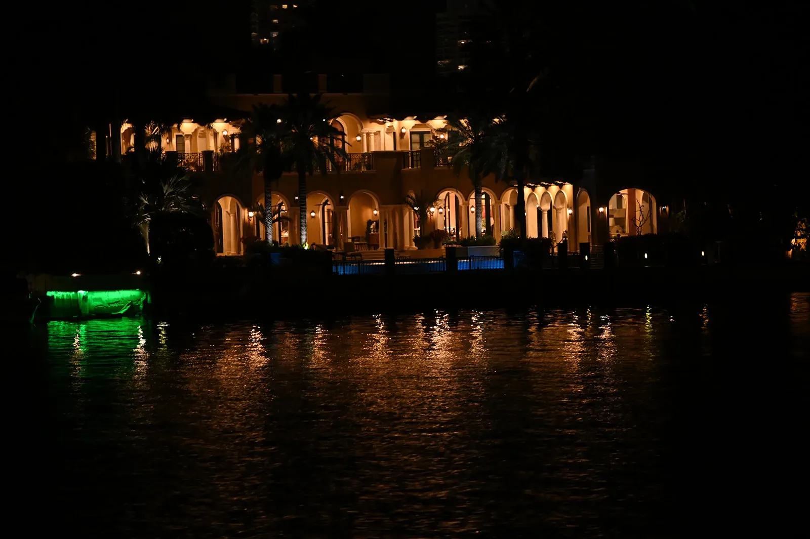 Luxury waterfront mansion illuminated at night during a Miami sightseeing cruise on Biscayne Bay