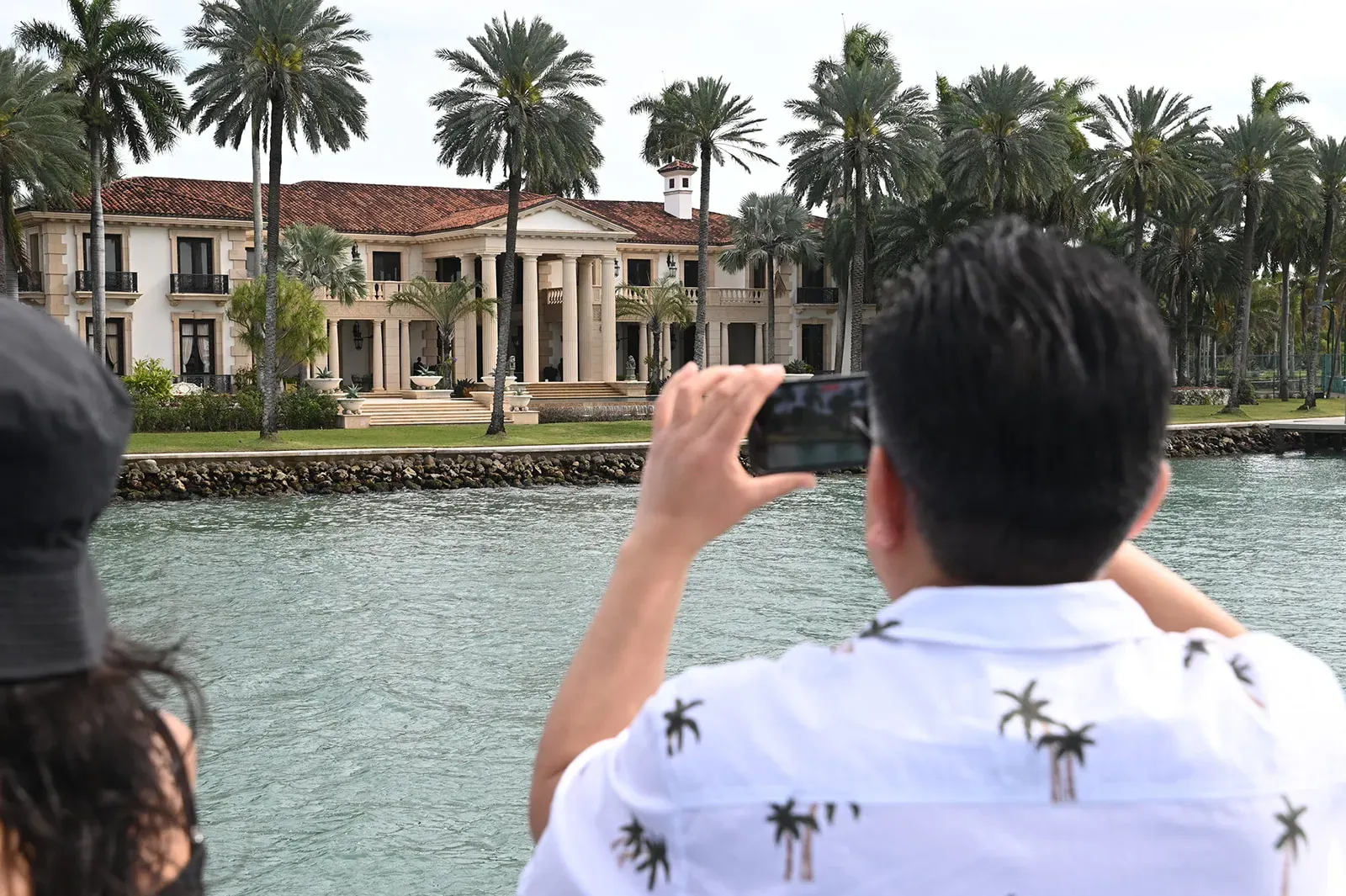 Guest photographing a waterfront mansion on Star Island during a Miami sightseeing cruise.