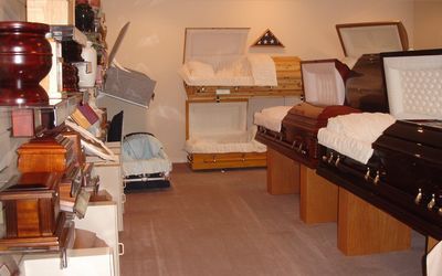 Furniture showroom with stacked wooden chairs, tables, and upholstered benches in a narrow display room