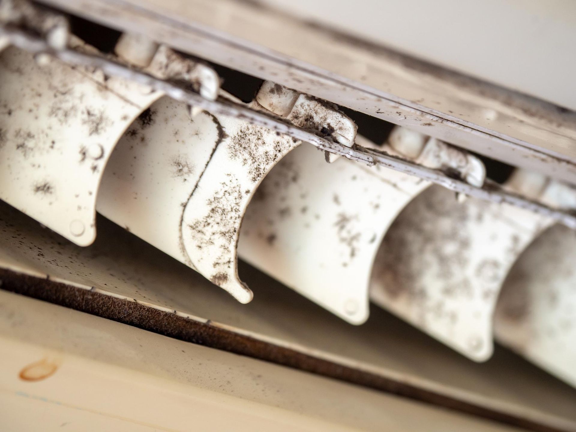 Dusty white air conditioner vents with dirt and debris buildup