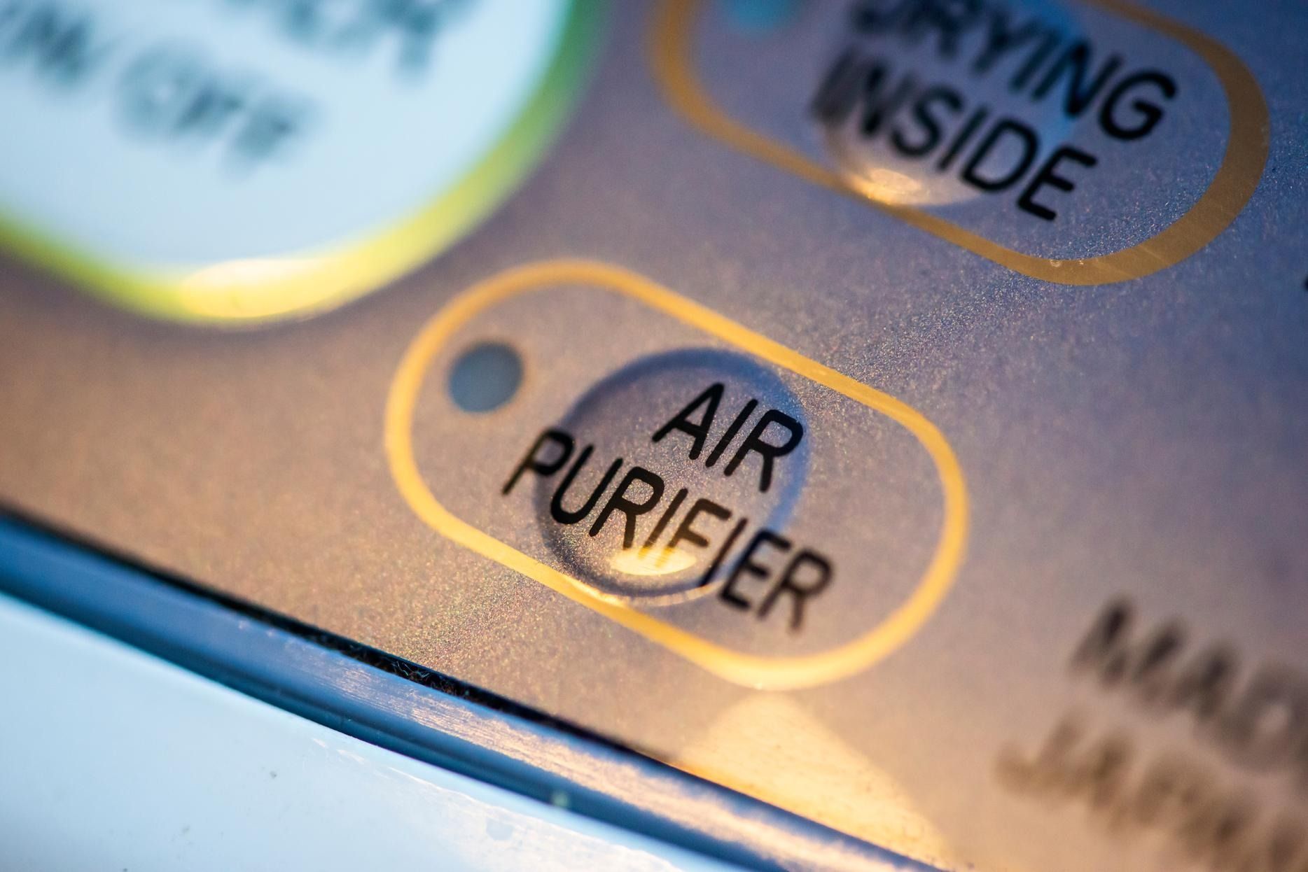 Close-up of an appliance control panel with an orange “AIR PURIFIER” indicator light.