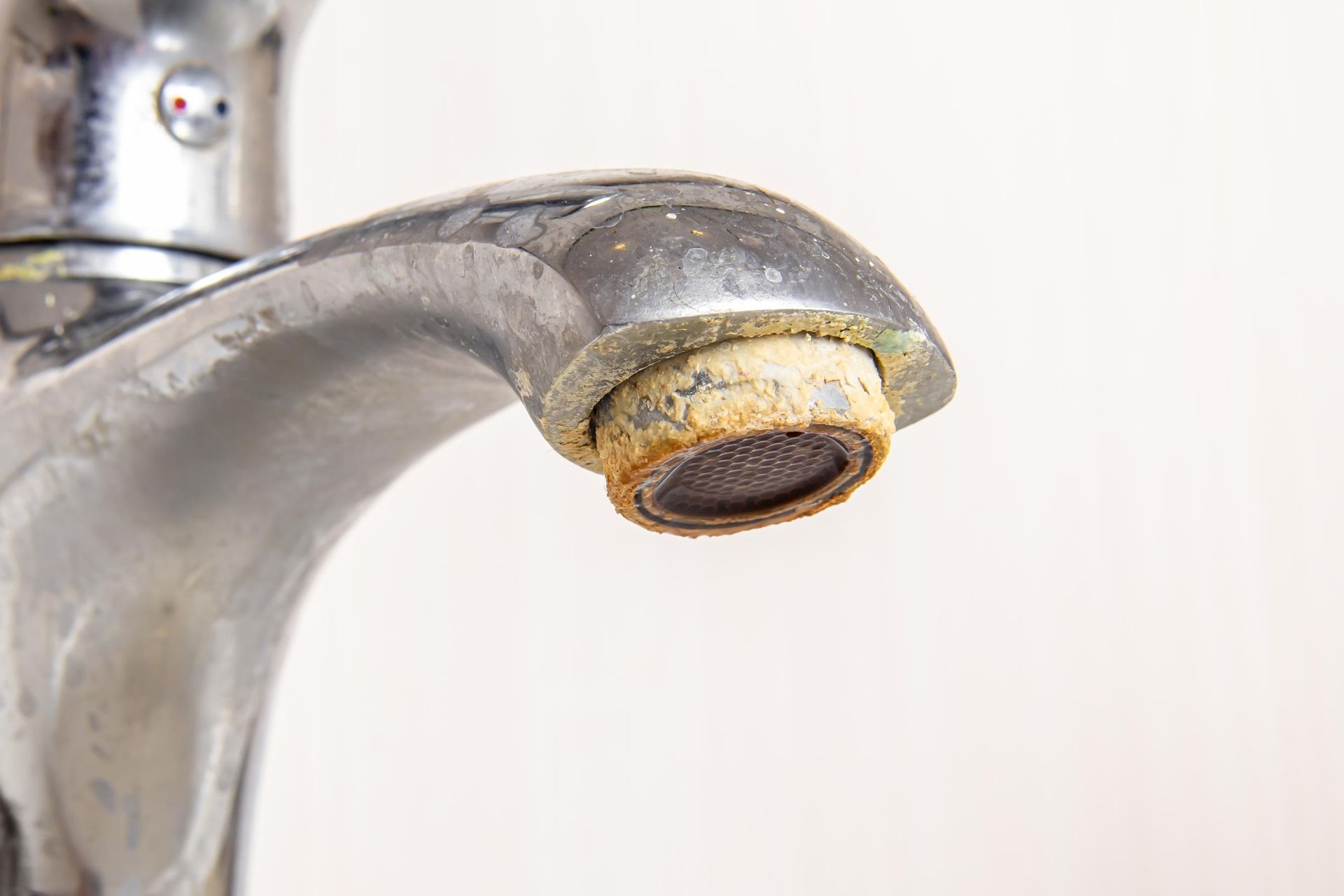 Close-up of a chrome faucet spout with mineral buildup on the aerator.
