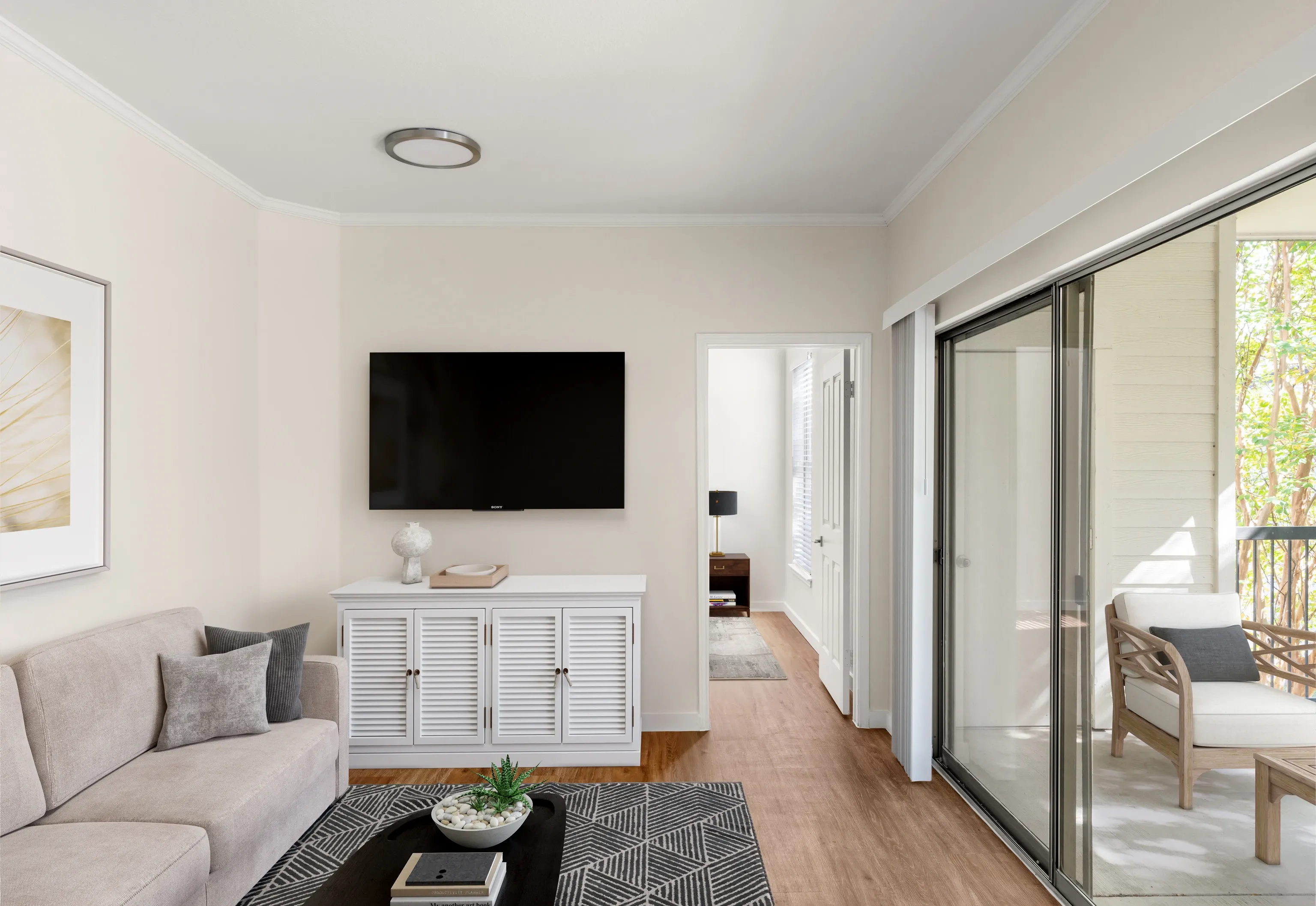 Living room with a sectional sofa, coffee table, media console, and a large television.