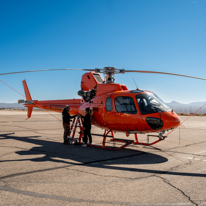 Technicians performing a Safran engine inspection on an Airbus AS350 helicopter on the ramp at Boulder City Municipal Airport
