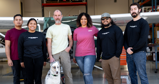 A group of Black Mountain Aviation technicians standing in front of an aircraft at the Boulder City hangar, representing FAA-certified avionics and maintenance services near Las Vegas.