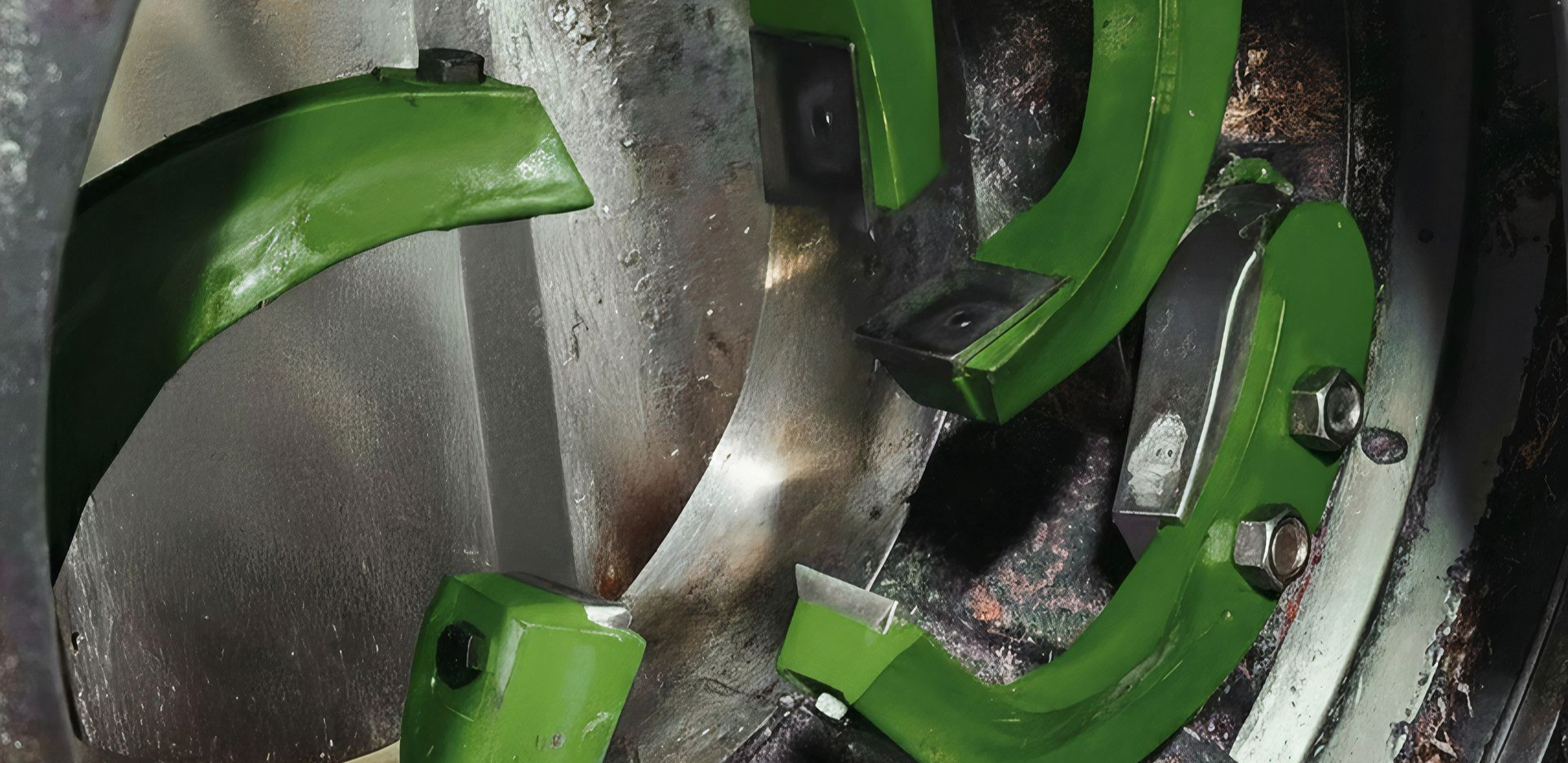 Close-up of green and silver metal parts inside a machine, coated with dust or debris