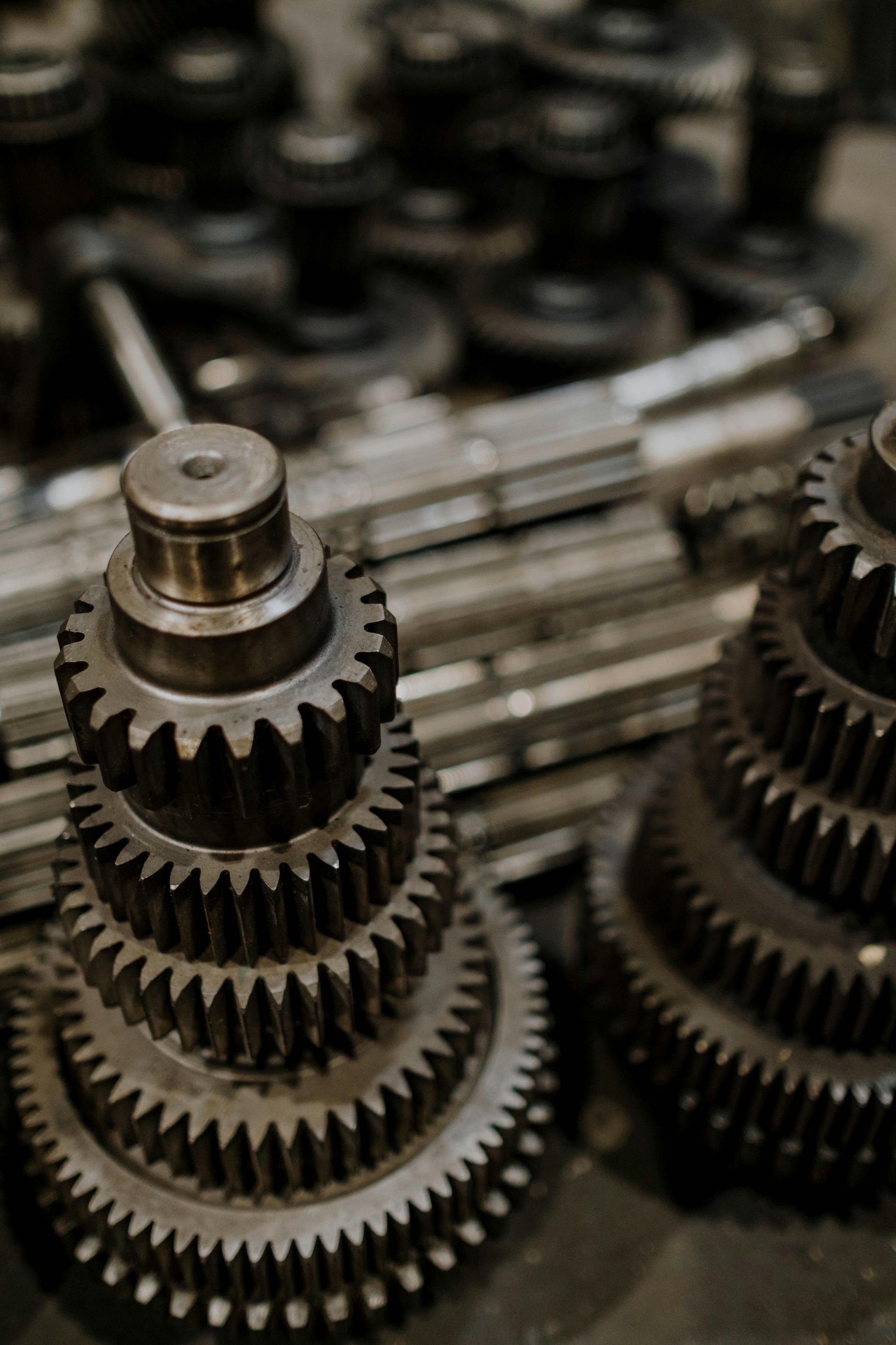 Stacked metal gears and shafts in a workshop, shown in close-up.