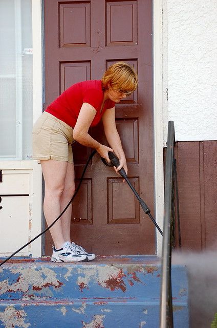 woman power washing concrete