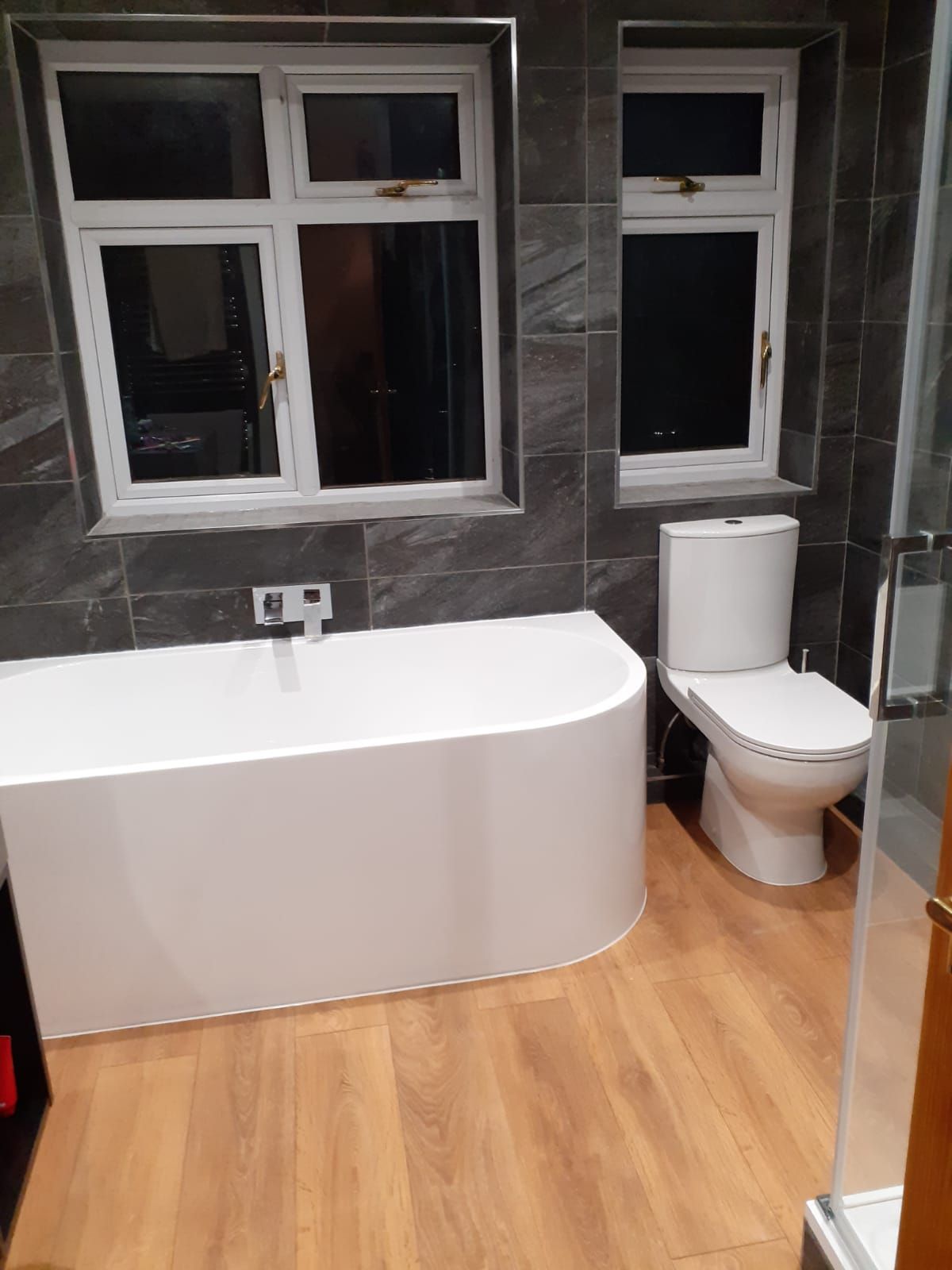 A white bathtub is sitting in a bathroom next to a window.