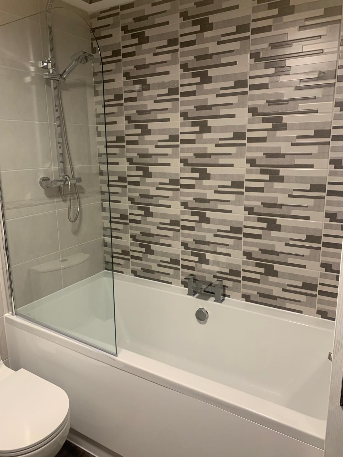 A bathroom with a toilet , sink , shower and mirror.
