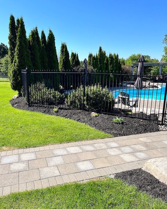 A fence surrounds a swimming pool in a backyard